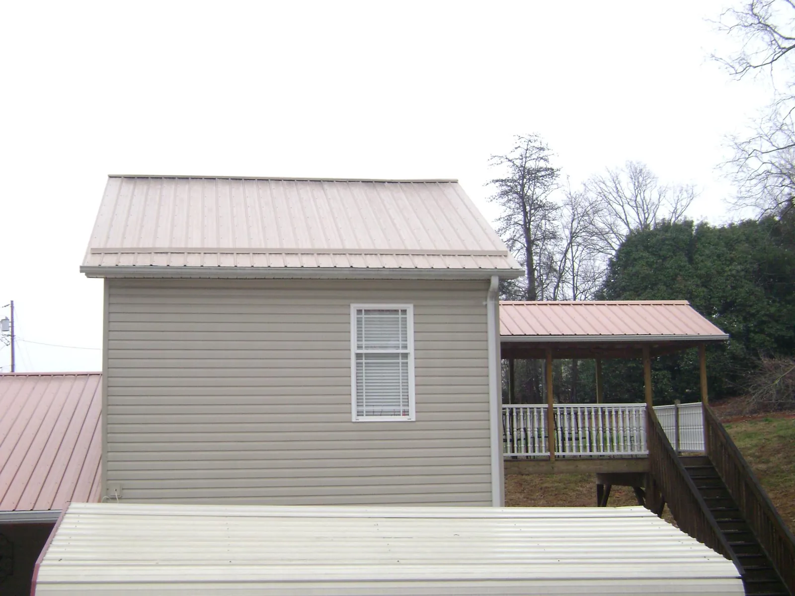 Tan metal roofs on a two story addition and attached porch, from a Roof Replacement job in Washington
