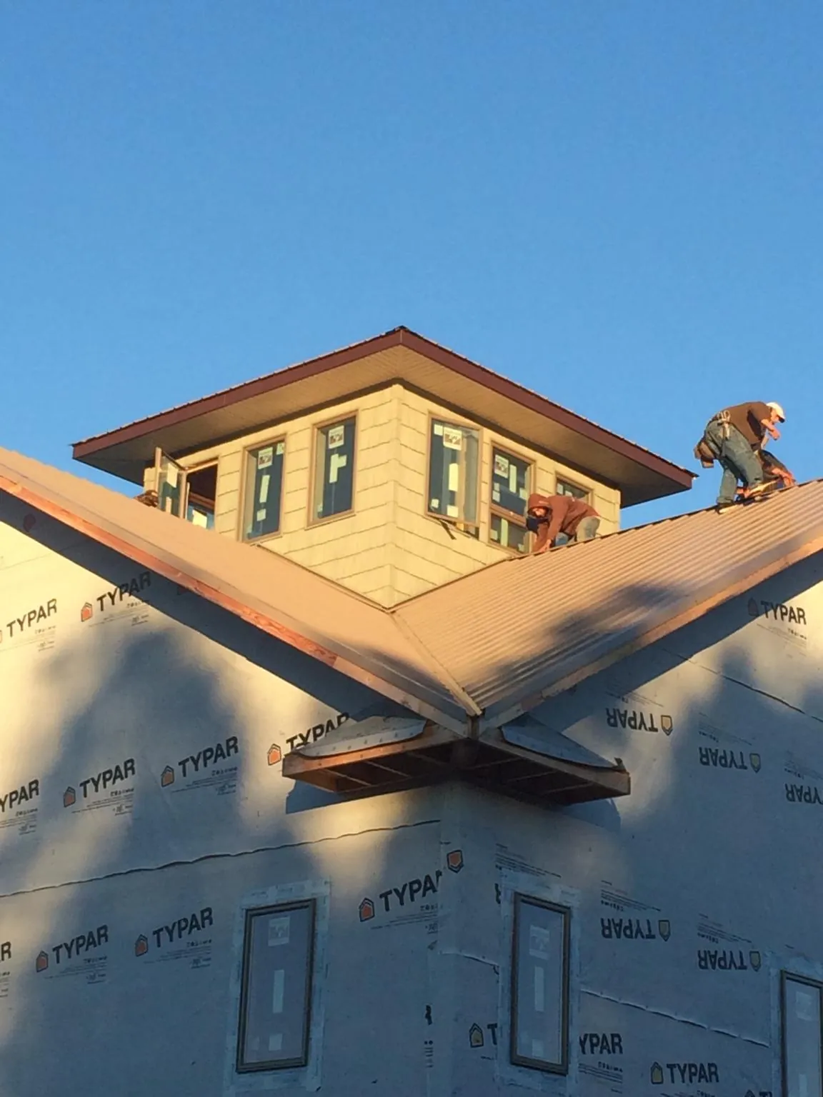 Roofers working around a rooftop cupola on a new metal roof at sunset — Roof Waterproofing in Washington by Roofing Brothers
